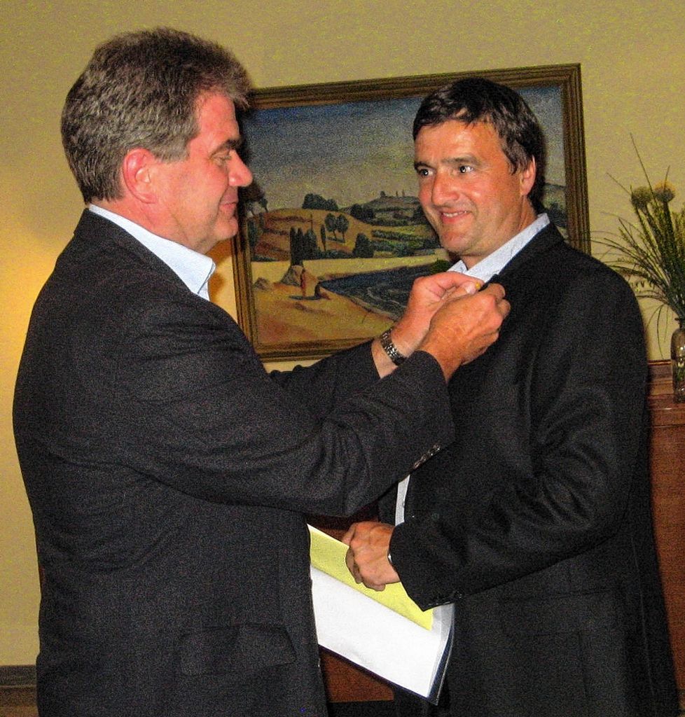 Arno Breitenfeld (l.) steckt seinem Nachfolger Klaus Ott als Präsident des Lions Clubs Müllheim-Neuenburg die Nadel an. Foto: Weiler Zeitung